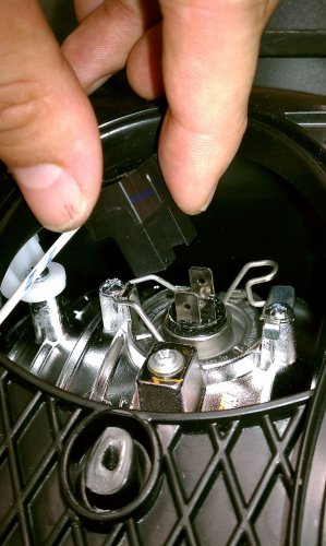 The bulb connector pulls straight off.  Notice that it is one unit.  The high-beam bulb has one connector on the bulb and a separate one on the bulb holder.  The high-beam bulb is also smaller.  Thus it's easy to determine which bulb is which.  However, to give yourself some additional maneuvering room, you may want to disconnect the high-beam connectors and remove the high-beam bulb as well.

