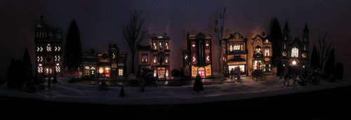 Panoramic view of the Christmas Village.  We used blocks meant for lifting beds up to raise the table as well as placing a folding dog corral around it to keep sticky little paws from playing with the minatures and getting fake, glittery snow all over the place.
