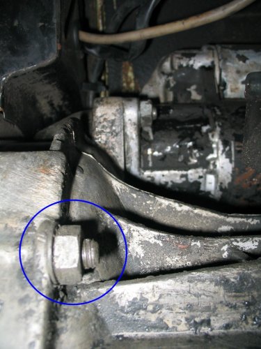 This is looking up at the tranny.  Circled is the left lower engine/tranny nut that needs to be removed, just like the right side (the nut is fastened to a stud).
