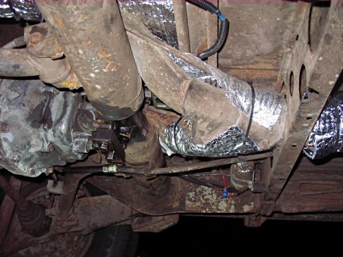 I wasn't able to fully wrap this piece.  It was a real pain to get the insulation on top of it.  Since it is already insulated from the factory I didn't worry much about cutting up some insulation and wrapping the bottom.  Maybe at a later date.  Notice that I did put an 18" sheet across the top of the heat exchanger ducts that go over the torsion housing.  What a pain in the neck!  Trying to wrap this section wasn't worth it, with the tubes, guides, wires, and shifter parts all in the way -- very busy area!
