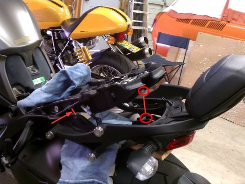 Removing the pillion backrest and grab handles is very easy.  There are only three, 6mm bolts.  One under the seat on each side (red arrow) and the other one is below the back rest mount, center-line of the seat.  Be careful when lowering it due to all the wiring.  I would also recommend covering the rear fender to protect both pieces from being scratched.
