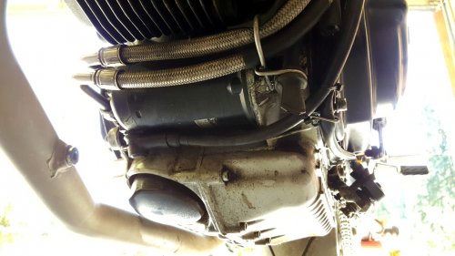 Looking under the engine from the front left side, shows the cable coming down from the left side and across the bottom of the engine to mount on the starter, 180-degrees from the OEM mounting.
