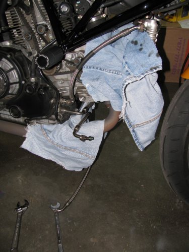 Rags in place to catch oil drippings and the Hypermotard line in position with the goofy bend end resting on the exhaust.  Remove the top connection first.  This way when you remove the bottom connection you can quickly move the stock line out of the way.
