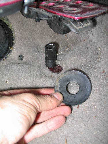 The round disc simply pulls off the accelerator pedal stop.  Carpet can then be lifted over the stop.
