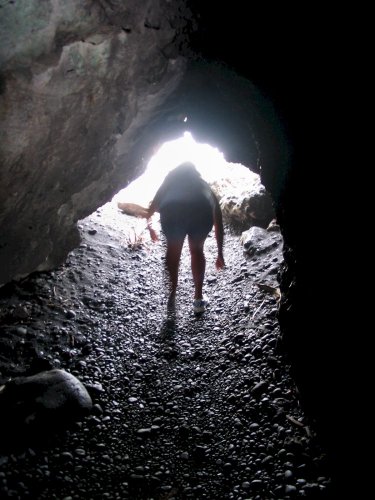 A short tunnel in the lava rock where the ocean crashes in.  Location is Waianapanapa Black Sand Beach
