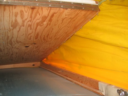 Yup, ya gotta rip the bed up as part of the removal process.  It's held down very well with long staples.  Bed can be removed through the hole in the roof.  So, after the Riviera is re-installed and screwed down, the bed bottom goes in last and is stapled down.
