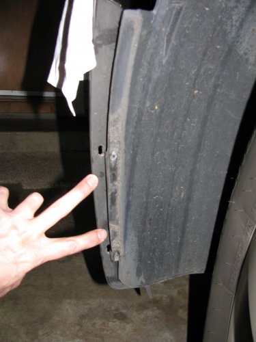 Remove the two screws that attach the wheel well splash guard to the front bumper skin (left side shown).
