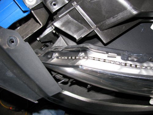 Showing the path of the LED array as it goes down on the front part of the head light.  That blue thing is simply a nylon auto trim tool I had laying nearby that I used to hold the fascia away from the head light so I could work with both hands.  Now just apply power from the turn signal tap!
