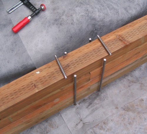 Making the rebar "staples"
Looking at the site, I decided to put rebar on the outside of the wood perimeter.  To give it a custom, finishing touch, I decided to weld the two pins together and thus give it a stapled look.  So I fired up the air compressor and dragged out my MIG welder (both Craftsman from Sears...very nice!).  After rebar is nailed into the earth and flush with the top of the lumber, cut top portion of rebar to length.  I kept the length short so the top piece only covered half of the top of the pin.  This gave an "L" profile, allowing plenty of space for placing a good welding bead.  Wire-wheel the ends clean and a spot for the MIG welding clamp to make good electrical contact.
