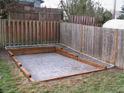 Contractor-grade weed barrier was laid down from the fence line to the outside edges of the lumber.  This picture shows the gray material in the main area where the shed will be placed.  The 1/2" round river rock is already laid into the area along the fence line.
