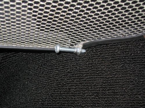 Looking underneath at how it stays in:  Four pointed screws push into the carpeting and, if really snugged tight, into the skin of the car.  This is the front right corner and there's a screw at each corner.  Thus the parcel tray is basically held in via expansion...it's pushes on the sides of the cabin wall.
