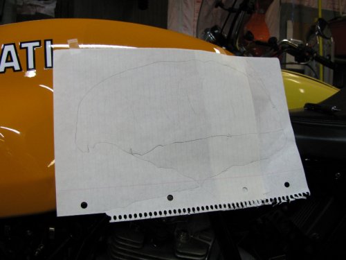 Tape some paper to the tank, sit on the bike, grip the tank, and trace around your legs.
