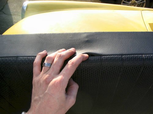 Slit in back edge of seat where original pull strap came from.  Pass the line through this slit.
