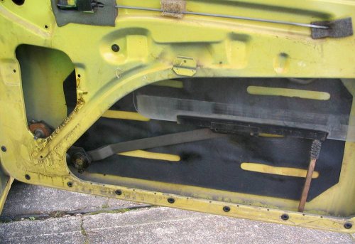 Insert winding mechanisim, lower glass a little, and slide locating spring into lifter channel (wire brush just used to hold window up for picture).  Bolt winding mechanisim back to door.  Replace everything, including the important vapor barrier (plastic sheet) as this protects the door card from water damage!
