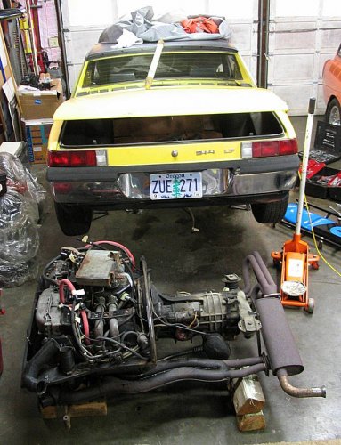 Out and resting on wood blocks.

Minimum engine/tranny dimensions for space needed are:
Width = 43"
Height = 21"
Length = 25" for engine
       = 48" for engine and tranny
       = 55" for engine, tranny and muffler
